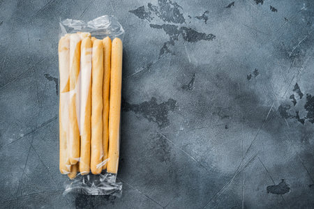 Breadsticks, with olive oil, on gray background, flat lay with copy space for text