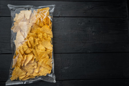 Corn traditional triangle nachos transparent pack, on black wooden background, top view or flat lay with copy space for textの写真素材