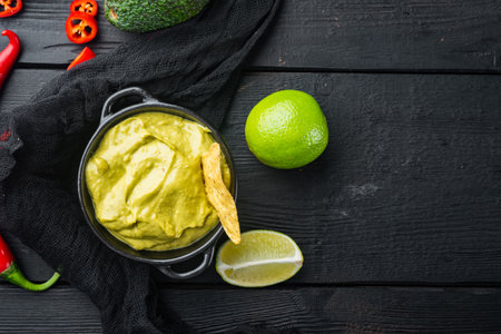 Avocado guacamole sauce in bowl, on black wooden background, top view or flat lay with copy space for textの写真素材