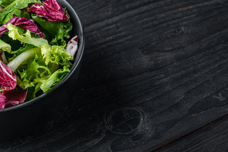 Fresh leaves of different lettuce salads, on black wooden table background with copy space for textの写真素材
