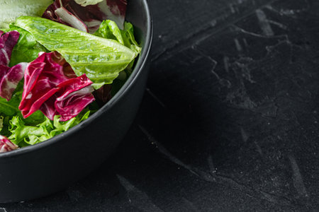 Bowls with mixed shredded salad lettuce fresh leaves, on black background with copy space for textの写真素材