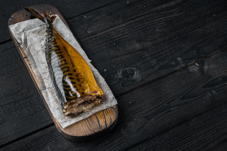 Smoked mackerel fish, on black wooden table background with copy space for textの写真素材