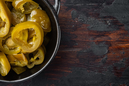 Green, organic pickled jalapenos in a bowl, on old dark wooden table background, top view flat lay with copy space for textの写真素材