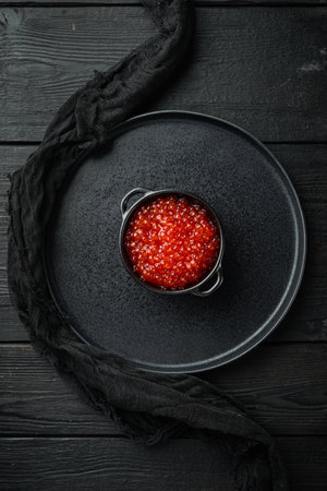 Bowl with delicious red caviar, on black wooden table background, top view flat layの写真素材
