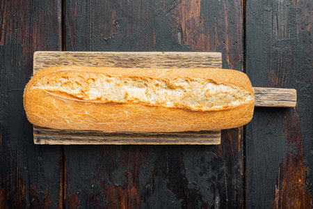Artisanal baguette bread, on old dark wooden table background, top view flat lay