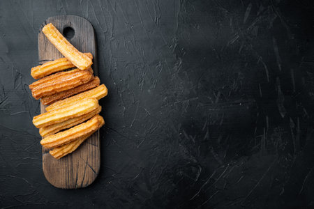 Churros sprinkled with powdered sugar set, on black background, top view flat lay with space for text, copyspaceの写真素材