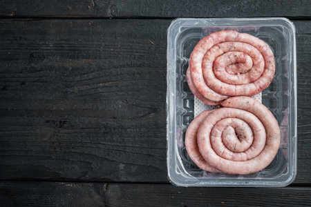 Raw meat sausage set, on black wooden table background, in plastic pack, top view flat lay, with space for text copyspaceの写真素材