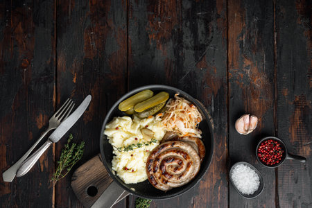 Bavarian fried sausage on sauerkraut in cast iron frying pan, on old dark wooden table background, top view flat lay, with space for text copyspaceの写真素材