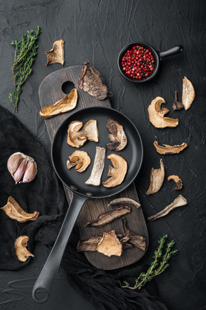 Dried wild mushrooms set in cast iron frying pan, on black background, top view flat layの写真素材