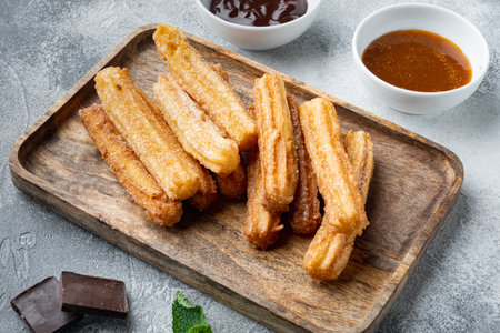 Typical Spanish snack churros, fried-dough pastry served usually with chocolate caramel hot sauce, on gray backgroundの写真素材