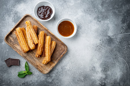 Churros with sugar and chocolate sauce, on gray background, top view flat lay with space for text, copyspaceの写真素材