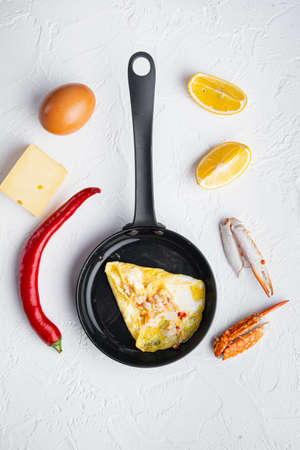 Fried breakfast omelette with a crab meat and cheese, on frying iron pan, on white background, top view flat layの写真素材