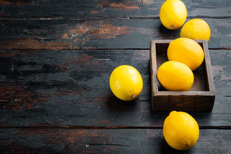 Fresh lemons set, in wooden box, on dark wooden background, with copyspace and space for textの写真素材
