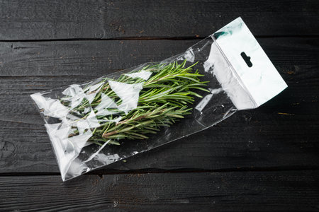 Rosemary in plastic bag set, on black wooden table background