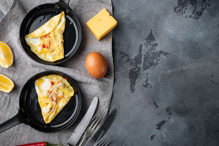 Thai Asian omelette, fresh red chilli, brown and white crabmeat, lemon, Cheddar cheese and eggs, on frying iron pan, on gray background, top view flat lay, with copyspace and space for textの写真素材