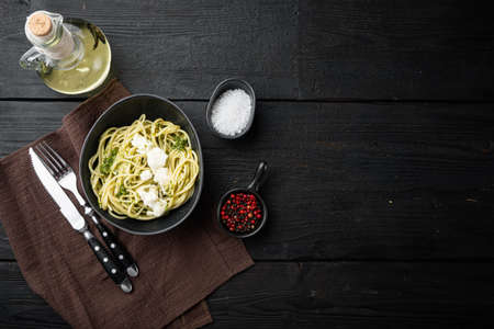 Italian spaghetti with homemade basil pesto with parmigiano, ricotta cheese set, in bowl, on black wooden table background, top view flat lay, with copyspace and space for textの写真素材