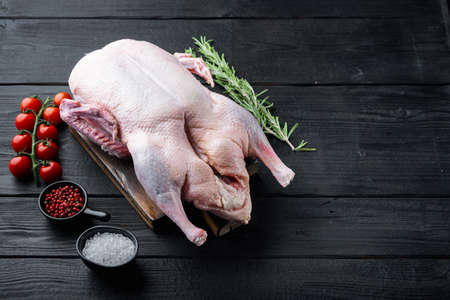 Fresh raw whole duck meat on black wooden background, with space for text.の写真素材