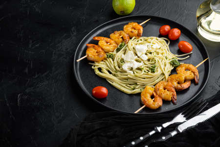 Zuccini spaghetti pasta with pesto and parmesan and prawns set, on plate, on black background, with copyspace and space for textの写真素材