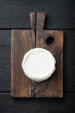 Italian organic, ricotta cheese, on wooden board, on black wooden table background, top view flat...