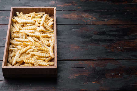 Frozen oven chips sliced potato set, in wooden box, on old dark wooden table background, with copyspace and space for textの写真素材