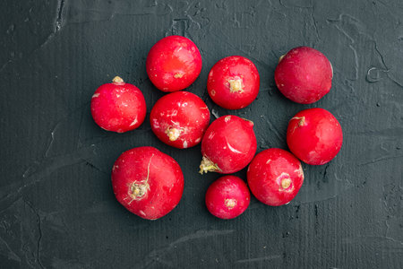 Bunch of ripe radishes set, on black background, top view flat lay