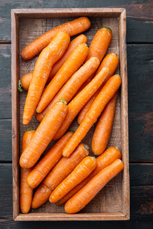 Beautiful ripe carrot background, in wooden box, on old dark wooden table background, top view flat...