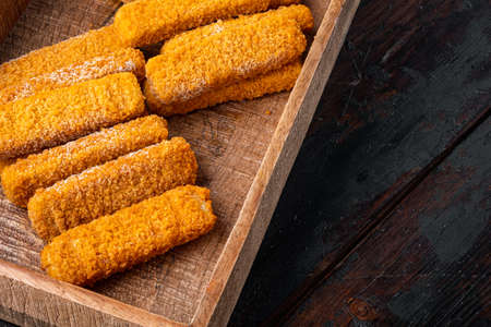 Frozen fish fingers, in wooden box, on old dark wooden table background , with copyspace and space for textの写真素材