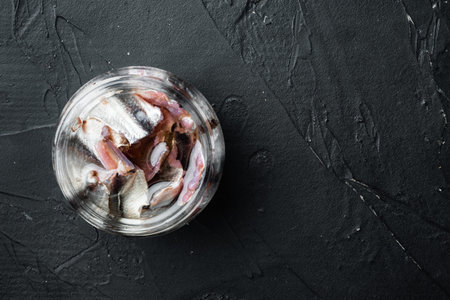 Pickled Anchovy set, in glass jar, on black background, top view flat lay, with copyspace and space...