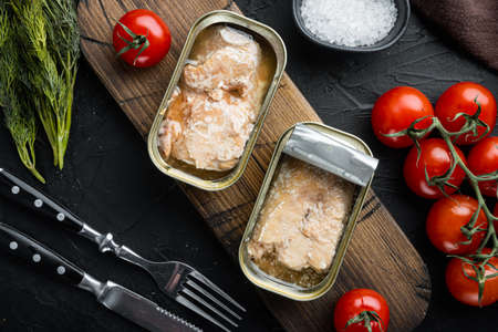 Canned wild Trout set, on wooden cutting board, on black background with herbs and ingredients, top view flat layの写真素材