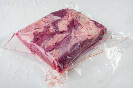Pastrami meat packed in vacuum plastic bags set, on white stone background, with copyspace and space for textの写真素材