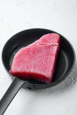 Raw organic tuna fillet. Seafood set, on frying cast iron pan, on white stone background