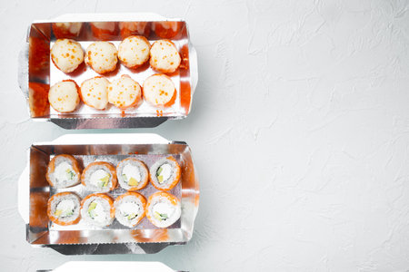 Tasty sushi rolls in disposable boxes set, on white stone background, top view flat lay, with...