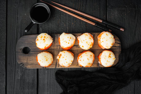 Baked sushi roll with shrimp and masago caviar cap. Traditional sushi restaurant dish set, on black...
