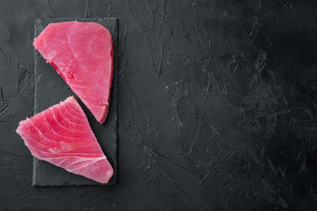 Fresh raw tuna steak set, on stone board, on black stone background, top view flat lay, with copyspace and space for textの写真素材