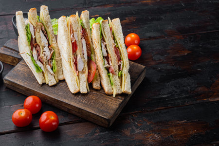 Sandwich with ham, cheese, tomatoe, lettuce, chicken meat and toasted bread, on old wooden table with copy space for textの写真素材