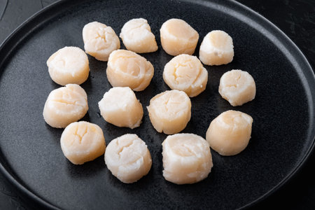 Fresh seafood, scallops meat, on black textured background