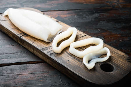 Seafood cuttlefish on cutting board over dark rustic wooden background, food photo.の写真素材