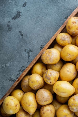 Fresh unpeeled baby potatoes set, in wooden box, on gray stone background, top view flat lay, with copyspace and space for textの写真素材