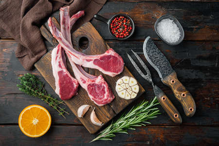 Raw Lamb chops set, with ingredients carrot orange, herbs, on old dark wooden table background, top view flat layの写真素材