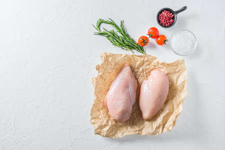 Raw chicken breast oon craft paper over textured white background top view space for textの写真素材
