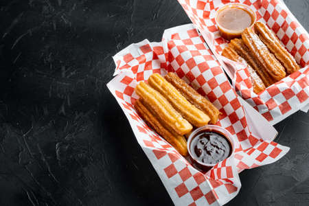 Spanish porras. Spanish food like spanish churros with chocolate, and caramel in paper tray, on black background with space for text, copyspaceの写真素材