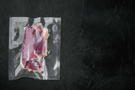 Vacuum packed raw duck breast set, on black stone background, top view flat lay, with copyspace and space for textの写真素材