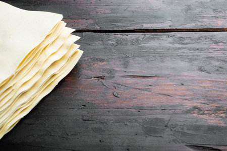 Lasagna dough sheets set, on old dark wooden table background, with copy space for text