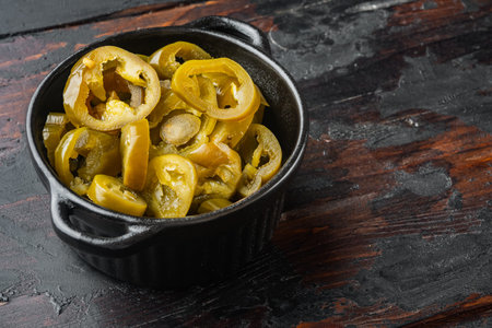 Jalapeno pickled and sliced, on old dark wooden table background with copy space for text