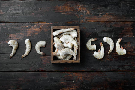 Frozen shell on Tiger Prawns or Asian tiger Shrimps set, on old dark wooden table, top view flat...