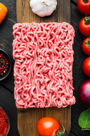 Bolognese sauce ingredients, minced meat tomatoe and herbs set, on wooden cutting board, on black wooden table background, top view, flat layの写真素材