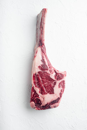 Piece of raw rib eye tomahawk or cowboy steak, raw fresh marbled prime beef set, on white stone...