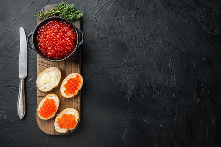 Canape toasts with red caviar, on black background, top view flat lay with copy space for text