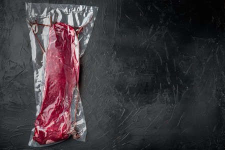 Raw beef tenderloin marbled meat in plastic pack set, on black stone background, top view flat lay, with copy space for textの写真素材