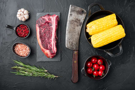 Raw fresh marbled meat black angus club steak and ingredients set, on black stone background, top view flat layの写真素材